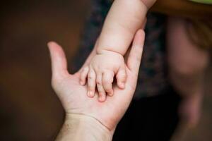 proche en haut image de du père et le sien bébé garçon fils mains en portant chaque autre. concentrer sur des doigts. photo