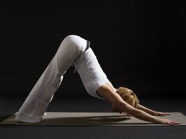 femme exercice yoga intérieur sur noir arrière-plan, photo