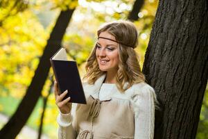 magnifique boho fille jouit en train de lire livre dans le parc. photo