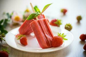 fait maison fraise la glace crème sur une bâton fabriqué de Frais des fraises dans une assiette photo