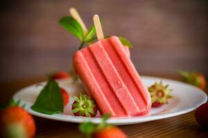 fait maison fraise la glace crème sur une bâton fabriqué de Frais des fraises dans une assiette photo