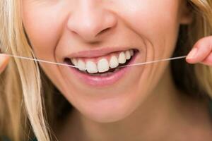 femme avec magnifique blanc les dents en utilisant dentaire soie. photo