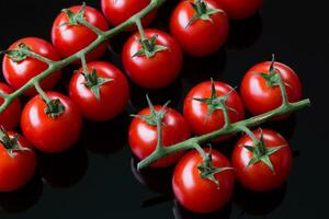 Frais Cerise tomates sur une noir Contexte. bouquet de Frais Cerise tomate sur une noir Contexte photo