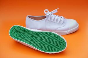 paire de Nouveau blanc Toile baskets, un spectacles vert caoutchouc en dessous de le des chaussures , Orange Contexte. confortable, à la mode. concept, des chaussures pour Faire sport ou exercice aussi pouvez porter pour en voyageant, randonnée. photo