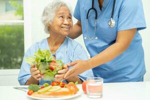 asiatique personnes âgées femme patient en mangeant Saumon steak petit déjeuner avec légume en bonne santé nourriture dans hôpital. photo