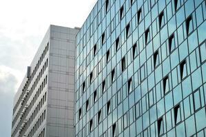 verre bâtiment avec transparent façade de le bâtiment et bleu ciel. de construction verre mur reflétant bleu ciel. abstrait moderne architecture fragment. contemporain architectural Contexte. photo