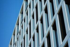 moderne Bureau bâtiment dans le ville avec les fenêtres et acier et aluminium panneaux mur. contemporain commercial architecture, verticale convergent géométrique lignes. photo