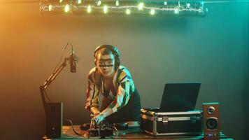 femme artiste mélange techno Chansons sur l'audio boutons, ayant amusement avec platines en jouant moderne la musique à boîte de nuit faire la fête. Jeune interprète essai basse contrôle clé, régler volume. trépied tir. photo