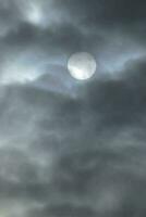 une plein lune dans le ciel avec foncé des nuages photo