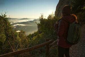 femme observe le nuageux paysage de le montagnes, très de bonne heure dans le Matin. photo