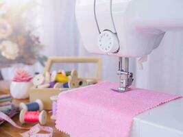 proche en haut de couture machine travail avec rose tissu, point Nouveau vêtements. photo