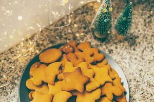 brillant gingembre biscuits arrangé sur plaque, niché contre le enchanteur lueur de Nouveau ans lumières photo