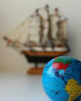 petit globe avec mappé Voyage itinéraires et défocalisé mâté navire jouet sur Contexte photo