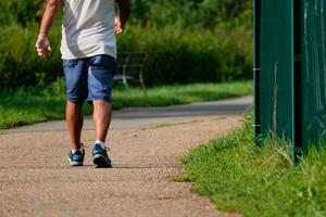 homme en marchant avec baskets sur une chemin, fermer de le sien jambes, des sports activité, en bonne santé style de vie photo