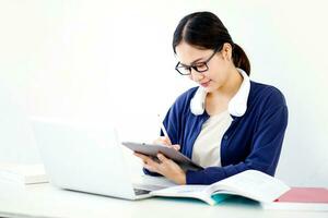 fermer asiatique Jeune femelle étudiant dans décontractée tissu faire une court Remarque sur tablette pour le examen sur blanc pente Contexte. asiatique école concept. photo