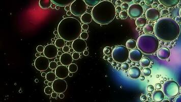 huile alimentaire colorée abstraite laisse tomber des bulles et des sphères qui coule sur la surface de l'eau photo
