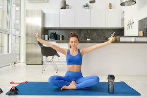 Jeune femme Faire des sports, méditer sur yoga tapis à maison, détient mains de côté et respiration, relaxant conscient des exercices photo