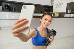 bien-être et des sports. magnifique Jeune femme prise selfie sur téléphone intelligent, Faire aptitude formation de maison, boisson eau, séjours hydraté et Faire des exercices photo