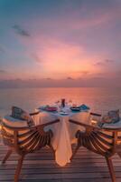 incroyable romantique dîner sur le plage sur en bois plate-forme bougies en dessous de le coucher du soleil ciel. romance et aimer, luxe destination dîner, exotique table installer avec mer voir. voyage de noces proposition conception photo