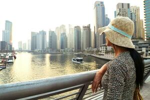 dubai, eau, 2022 - belle femme touristique caucasienne en robe d'été à la mode profitez de la marina de dubai aux émirats arabes unis. saison touristique de luxe et de confort photo