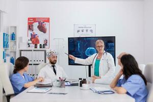 hôpital médical équipe Faire cerveau activité recherche en utilisant casque avec capteurs surveillance radiographie compétence. médecin médecins en cours d'analyse maladie traitement travail dans conférence réunion pièce photo