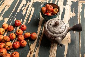 l'aubépine rouge dans l'assiette et la théière sont sur la table en bois photo