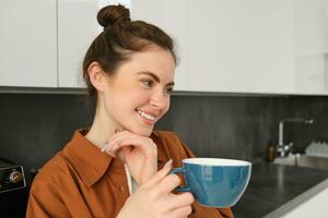 magnifique Jeune femme avec gros tasse de café, souriant et à la recherche content photo