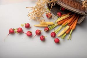 les radis rouges et oranges sont sur le drap blanc photo