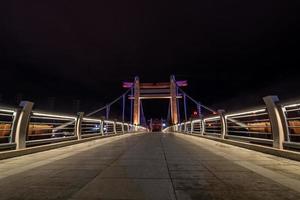 la nuit, le ruisseau reflète les lumières colorées sur le pont