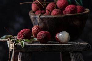 le litchi est placé dans une assiette en bois, pelée ou non ouverte, sur une table à grain de bois foncé photo