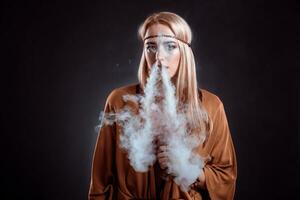 Jeune femme dans le boho style soufflant fumée photo