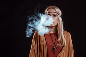 Jeune femme dans le boho style soufflant fumée photo