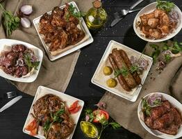 grillé agneau kebab, des chachliks, poulet tabaka et ailes sur noir table photo