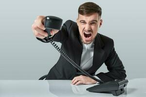 Jeune homme cadrans le téléphone nombre tandis que séance dans le Bureau photo