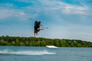 Masculin wakeboarder sauter plus de l'eau avec planche en portant corde photo