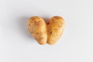 cœur en forme de patates sur une blanc Contexte. laid nourriture, la Saint-Valentin journée concept. photo