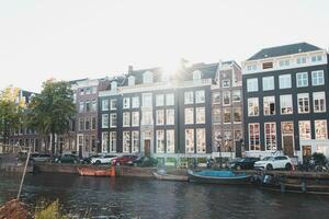 le coucher du soleil illumine une l'eau canal et adjacent bâtiments dans le Capitale ville de amsterdam, le Pays-Bas. Venise de le Nord photo