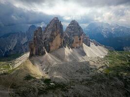 aérien vue de tre cime di lavaredo Montagne pendant une nuageux journée avec peu Soleil ouvertures dans le dolomites, Italie. spectaculaire et cinématique paysage. très célèbre des endroits pour randonnée et Roche escalade. photo