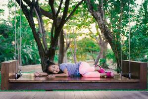 peu asiatique fille est pose vers le bas sur le gros balançoire dans le parc photo