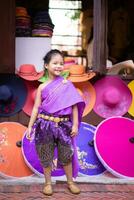 peu asiatique fille dans thaïlandais période robe permanent avec coloré parapluie photo