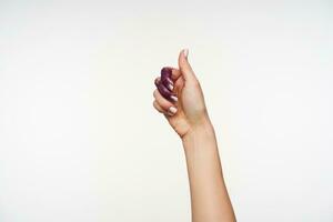 studio photo de jolie féminin main avec violet scintille sur il montrant élevé pouce tandis que exprimer positif émotions, posant plus de blanc Contexte