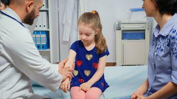 fille ayant des douleurs car de bras pendant médical vérification. soins de santé praticien médecin médecin spécialiste dans médicament fournir santé se soucier prestations de service consultation traitement dans hôpital cabinet photo