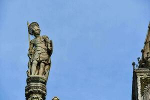 statue de une homme en portant une épée sur Haut de une bâtiment photo