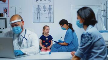 infirmière avec protection masque l'écriture enfant Les données sur presse-papiers pendant COVID-19 [feminine. médecin spécialiste dans médicament fournir santé se soucier prestations de service consultation, traitement, examen dans hôpital cabinet photo