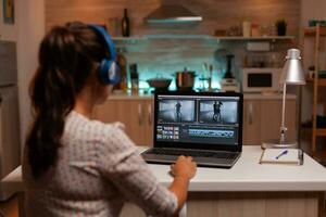 brunette vidéo éditeur travaux avec métrage sur personnel portable dans Accueil ktichen pendant nuit temps. contenu créateur dans Accueil travail sur montage de film en utilisant moderne Logiciel pour édition en retard à nuit. photo