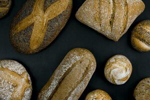 différent les types de fraîchement cuit pain sur une noir Contexte. photo