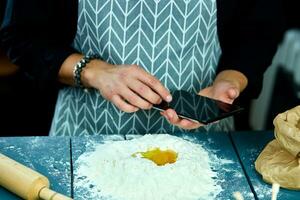 homme en utilisant électronique tablette PC dans cuisine pour pâtisserie. photo