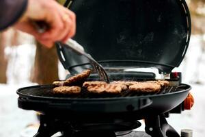 homme grillage steaks sur une portable un barbecue, neigeux hiver barbecue photo