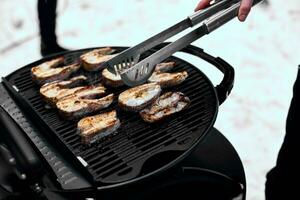 homme grillage délicieux poisson sur une portable un barbecue, neigeux hiver barbecue photo