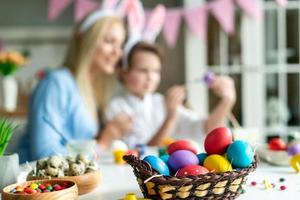 gros plan, oeufs colorés, sur fond flou de la mère et de son fils mignon. photo